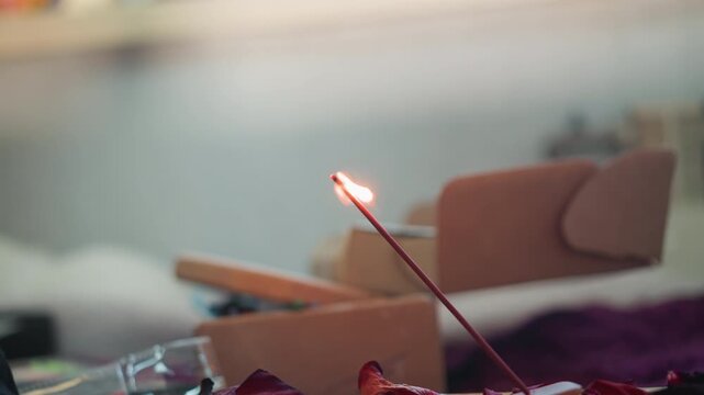 Incense stick burning on altar, closeup of flame and drifting smoke, warm cozy bokeh background, practitioner lighting for quiet divination and meditation, slow smoldering ember and ash