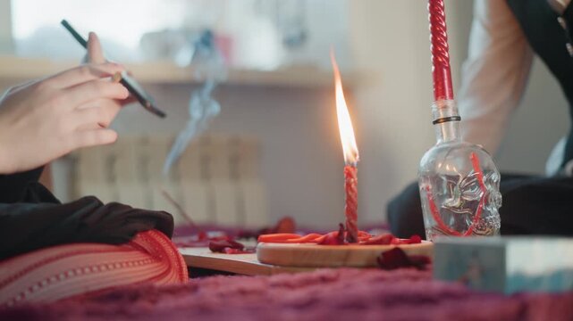 Caucasian woman hands near burning candle on velvet table, incense smoke curling from an altar bottle, closeup of ritual tools and phone intimate fortune telling session with tarot vibes, moody