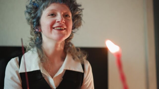 Gentle gestures illuminate cozy interior space. Serene imagery of smiling reader with flames and incense. Cheerful individual with curly hair offers comforting stories and warm gestures