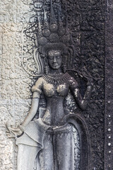 Fototapeta premium Apsara dancer carving on the walls of Angkor Wat temple complex in Siem Reap, Cambodia. These celestial dancers are depicted in ancient Khmer art.