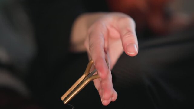 Focused hand with pendulum. Serene scene of mystical practices with focused movement and oil. Tranquil moment captured with hand holding brass pendulum dripping oil during mystical ritual