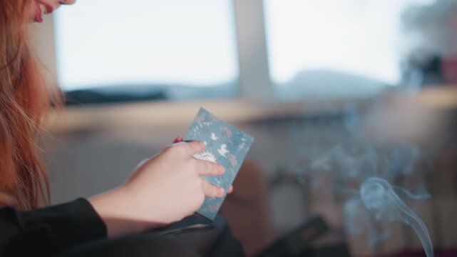 Intimate tarot reading redhead seeker, fortune teller studies cards and candle smoke in sunlit room, closeup of hands flipping tarot deck, vintage glass bottle, soft cinematic bokeh, moody cozy