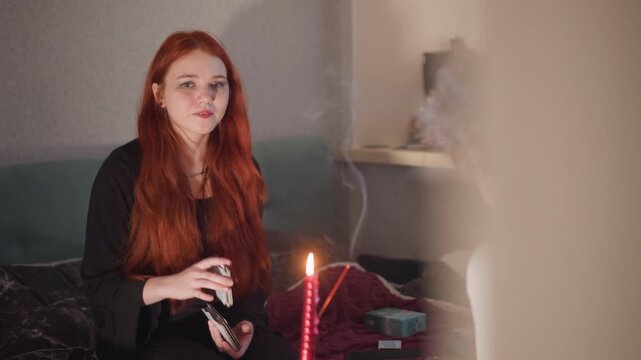 Serene woman engages in tarot card reading. Warm candlelit environment with woman practicing tarot readings. Tranquil setting with smiling woman reading tarot cards near softly glowing candle