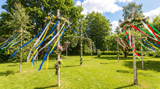 Midsummer backyard with multiple decorated maypoles and ribbons for greeting card poster social media summer festival celebration holiday advertising campaign garden decoration