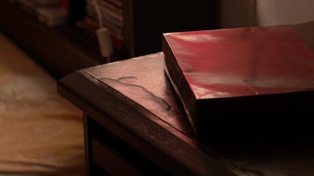 Cinematic pan shot to mysterious red box on wooden nightstand in dark bedroom