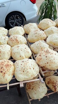Vertical Close Up of Egyptian Aish Baladi Flatbreads with Sesame Seeds Cooling on Outdoor Rack