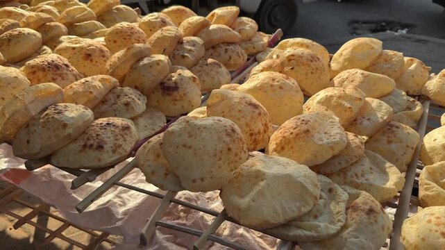 Freshly Baked Egyptian Aish Baladi Flatbreads Arranged on Cooling Rack at Street Bakery at sunset