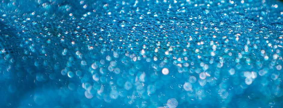 Close up of blue fabric with water droplets. Soft focus.