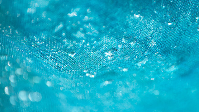 Close up of blue fabric with water droplets. Soft focus.