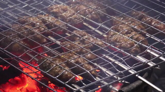 Kofta kebabs grilling over glowing charcoal with rising smoke