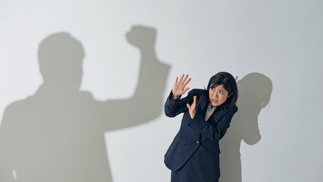 男性のシルエットに叩かれる女性ビジネスパーソン
