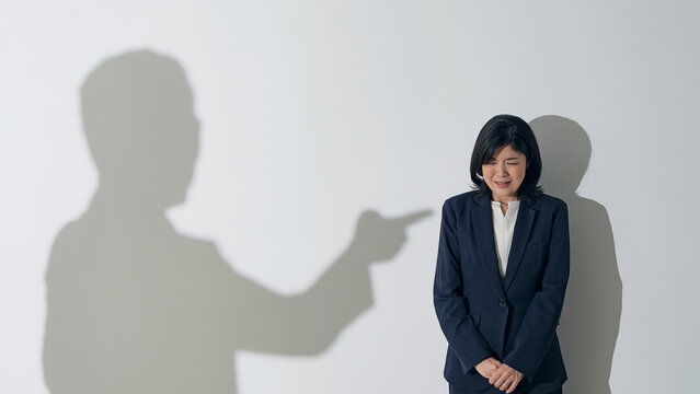 男性のシルエットに叱責される女性ビジネスパーソン