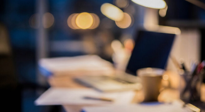 A cozy workspace illuminated by warm light, featuring a laptop, scattered papers, and a coffee cup. The blurred background creates an inviting ambiance for productivity.