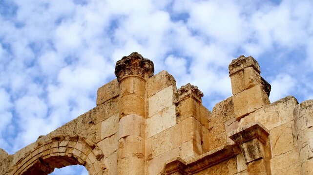 Low angle timelapse of ancient Roman ruins and Corinthian columns at Jerash archaeological site in Jordan. Moving white clouds over the stone architecture of the Decapolis city of Gerasa