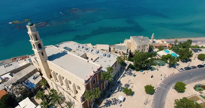 Aerial orbit shot around St. Peter&rsquo;s Church in Old Jaffa, Israel. Mediterranean coastline, turquoise sea, historic architecture and waterfront scenery captured by drone.