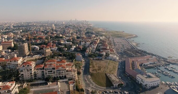 High-quality drone flyover from Jaffa toward Tel Aviv skyline in Israel. Mediterranean coast, marina, beachfront cityscape and urban skyline captured from the air.