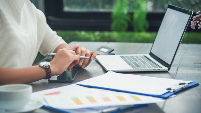 Asian female people working office firm with business stuff, coffee cup. Asian Woman Hands writing planning on office paper use calendar from laptop. Female hand holding pen work Business Plan.
