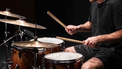 Fototapeta premium Close up of a drummer performing on a drum kit with a black background