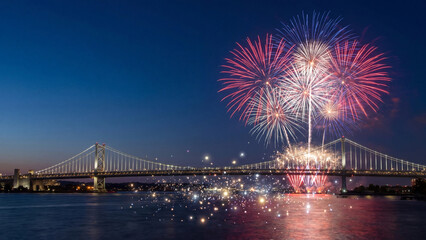 Bridge spans across a wide river while spectacular fireworks explode in the dark sky above the illuminated structure during a grand public holiday festival at night.