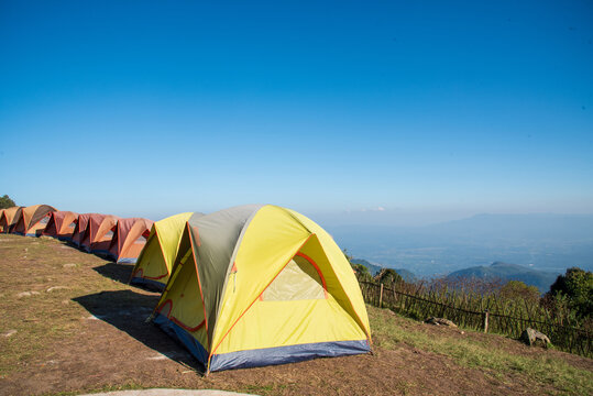 Tent camp in nature background with sunrise on top of mountain. Tent Camping trip outdoor hiking mountain hill. Adventure Travel wildness flare sunlight. Picnic tent green nature campground in forest