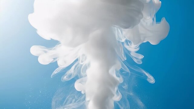 White ink dispersing in blue water creating swirling patterns