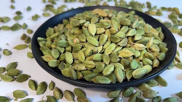 Close-up of green cardamom pods, 16:9 widescreen footage, rotating shot from left to right, healthy organic spices, aromatic food ingredient, nutrition, macro shot of cardamom