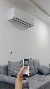 Turning on the air conditioner with a remote control, 9:16 vertical video, adjusting climate control, home comfort, cooling the room, modern HVAC system, lifestyle.