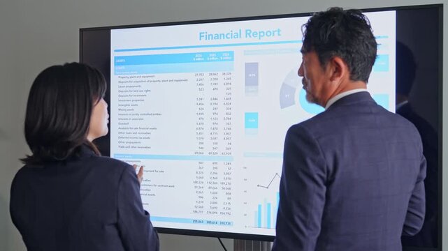 画面を見ながら会話するビジネスパーソンのグループ