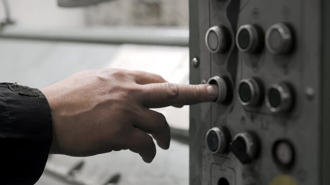 Close up of factory worker operating industrial machine control panel and pressing control buttons during automated manufacturing process