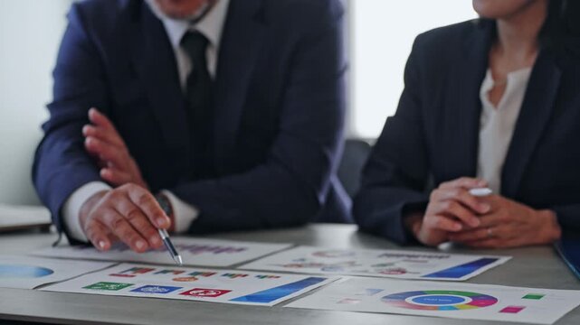 Male and female business professionals holding a meeting while looking at documents.