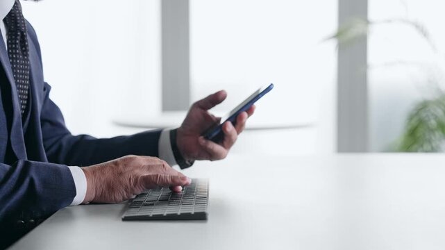 スマホとPCを使って作業する男性ビジネスパーソン