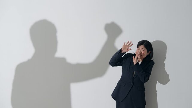 男性のシルエットに叩かれる女性ビジネスパーソン