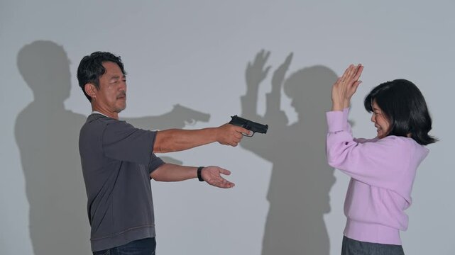 女性に拳銃を突きつける男性