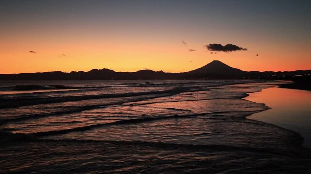 鵠沼海岸にて、日没後のオレンジ色に染まる波打ち際と富士山のシルエット　夕景