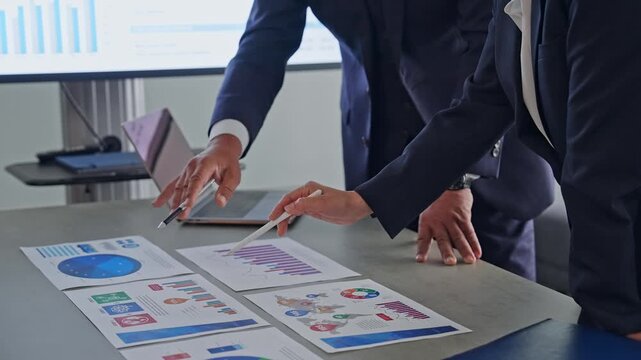 A group of business people talking while looking at documents.