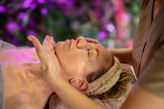 Anti-aging feminine beauty treatment routine and body care, masseuse making facial massage for woman client, lady relaxing on spa bed in luxury salon while cosmetologist performing lifting procedure