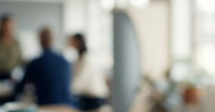 An abstract view of a collaborative workspace with blurred people engaged in discussion. The setting is modern and promotes teamwork and creativity.