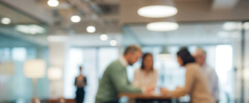 A group of professionals collaborates around a table in a bright, modern office setting, with blurred figures enhancing the focus on teamwork and communication.