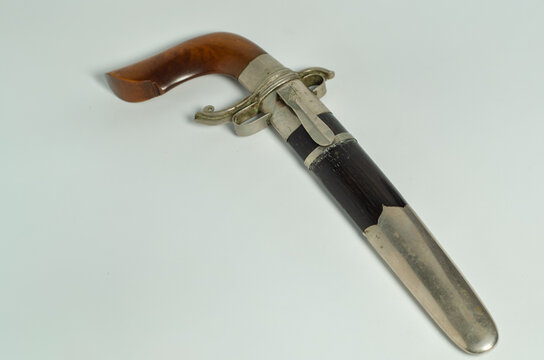 Handcrafted Bugis Gecong blade with a wooden sheath and handle, isolated on a white background for cultural and historical themes.