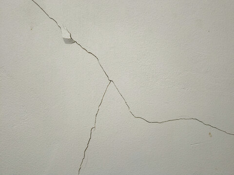 Cracks on a white wall surface indicating structural wear or plaster damage