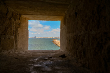 Obraz premium View of the Mediterranean sea and Alexandria cityscape through a fortress shooting window at Qaitbay Citadel