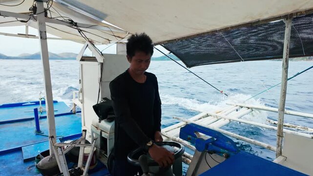 Filipino skipper navigates traditional banca through scenic Palawan seascape