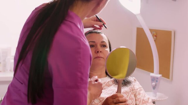 Aesthetician marking face. Beauty skin. Professional beautician drawing correction lines contour on woman client for plastic surgery procedure.
