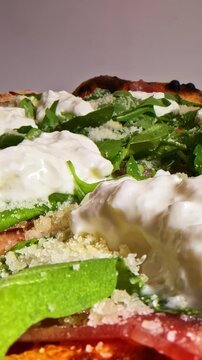 Macro camera movement over artisanal italian pizza with premium stracciatella cheese and fresh rocket salad on crispy baked crust served at pizzeria restaurant