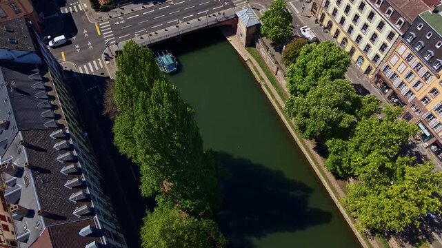 Tourist boat passing under Pont de Pierre bridge on Canal du Faux-Rempart in Strasbourg, France. Aerial top-down view