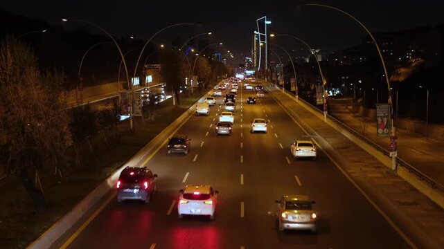 Nighttime urban traffic scene featuring illuminated Ankara boulevard, moving vehicles, and glowing city lights across busy capital roadway