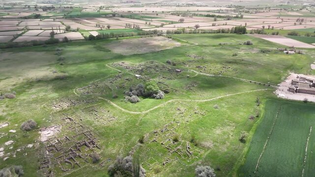 Drone aerial view of Gordion Ancient City ruins surrounded by green farmland and archaeological landscape in Ankara Province Turkey