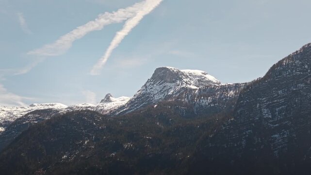 Wide mountain landscape in Banff National Park Alberta Canada featuring snow covered Mount Rundle beneath blue sky with wispy clouds above rugged peaks