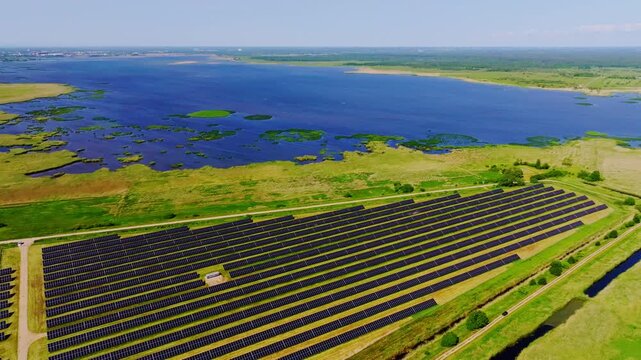 Drone slowly backward above photovoltaic panels near Liepaja lake shoreline