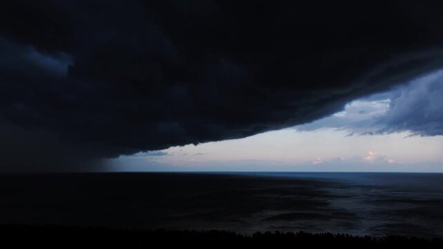 Dark thundercloud shelf advances above Baltic waters as rain falls near horizon